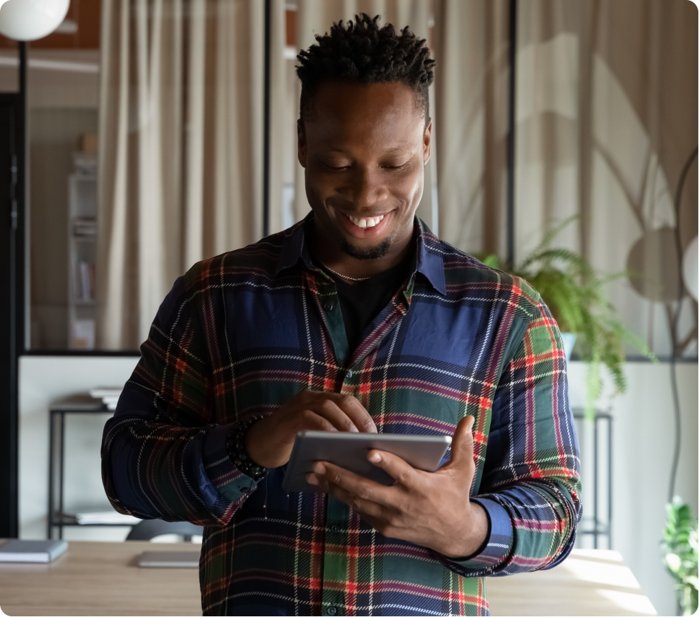 middle age man smiling while using tablet device in a plaid shirt
